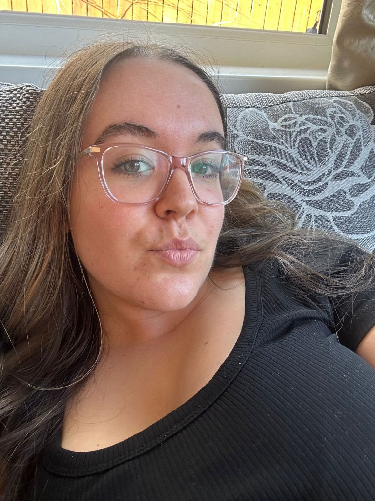 Eva, smiling at the camera in glasses and a black top